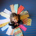 Five year old, C, sits center circle in the order of fabrics arranged solely by her.