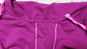 I find the stitching to be very inconspicuous on the exterior neckline (often hidden by the hood).